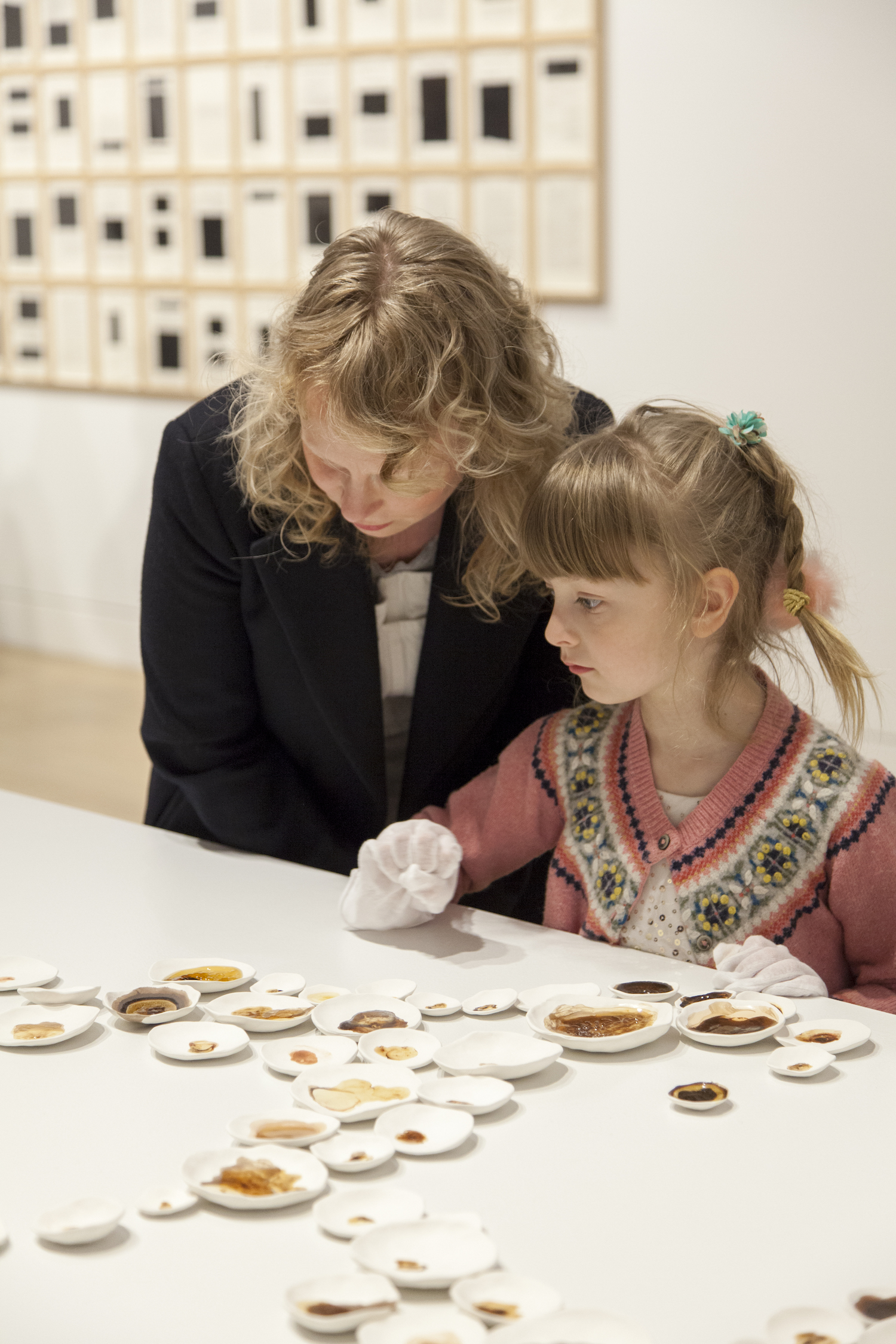 Adult and child observing small dishes of brown pigments