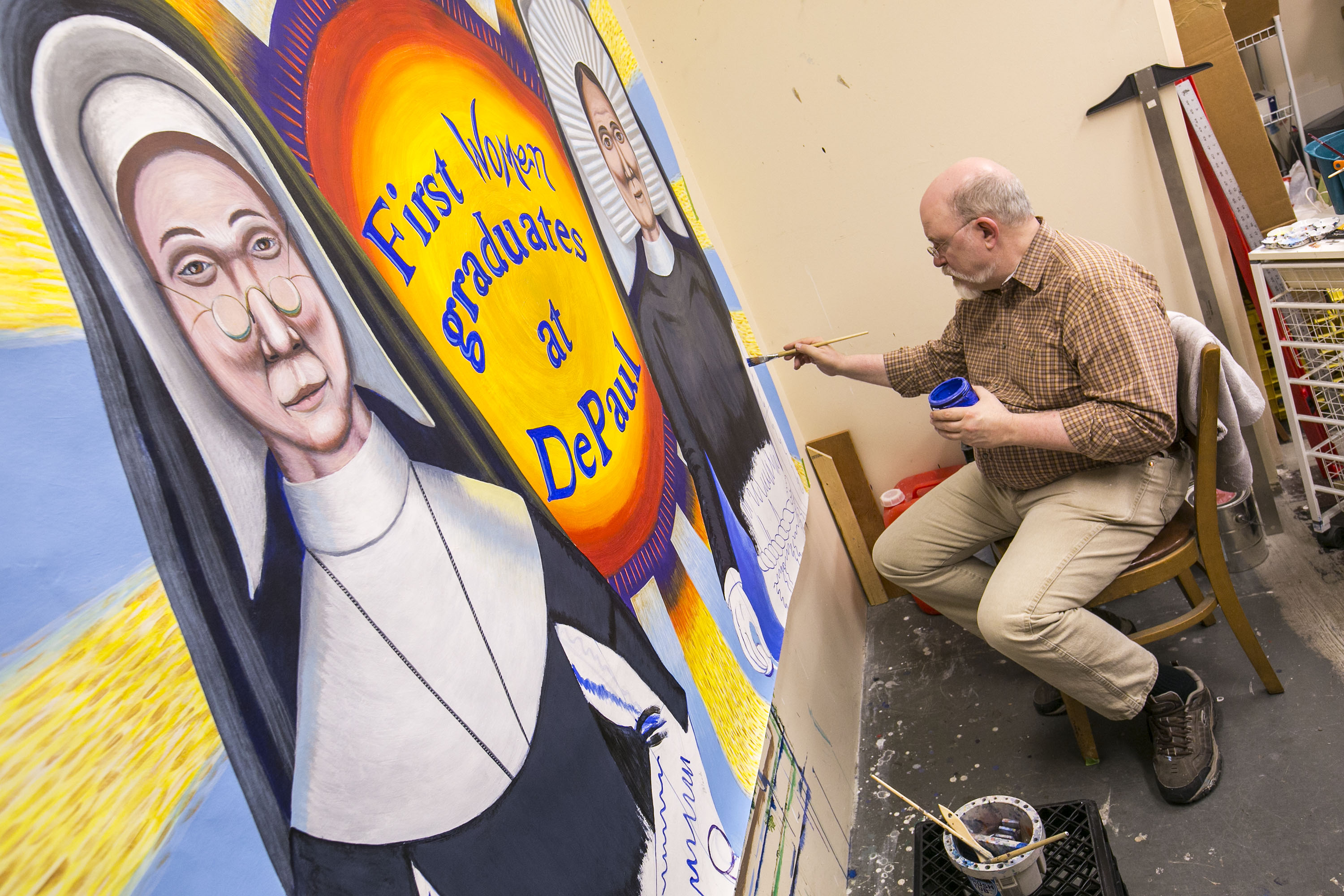 Brother Mark Elder, C.M., adds the finishing touches to the mural depicting the first women graduates of DePaul University.  (DePaul University/Jamie Moncrief)
