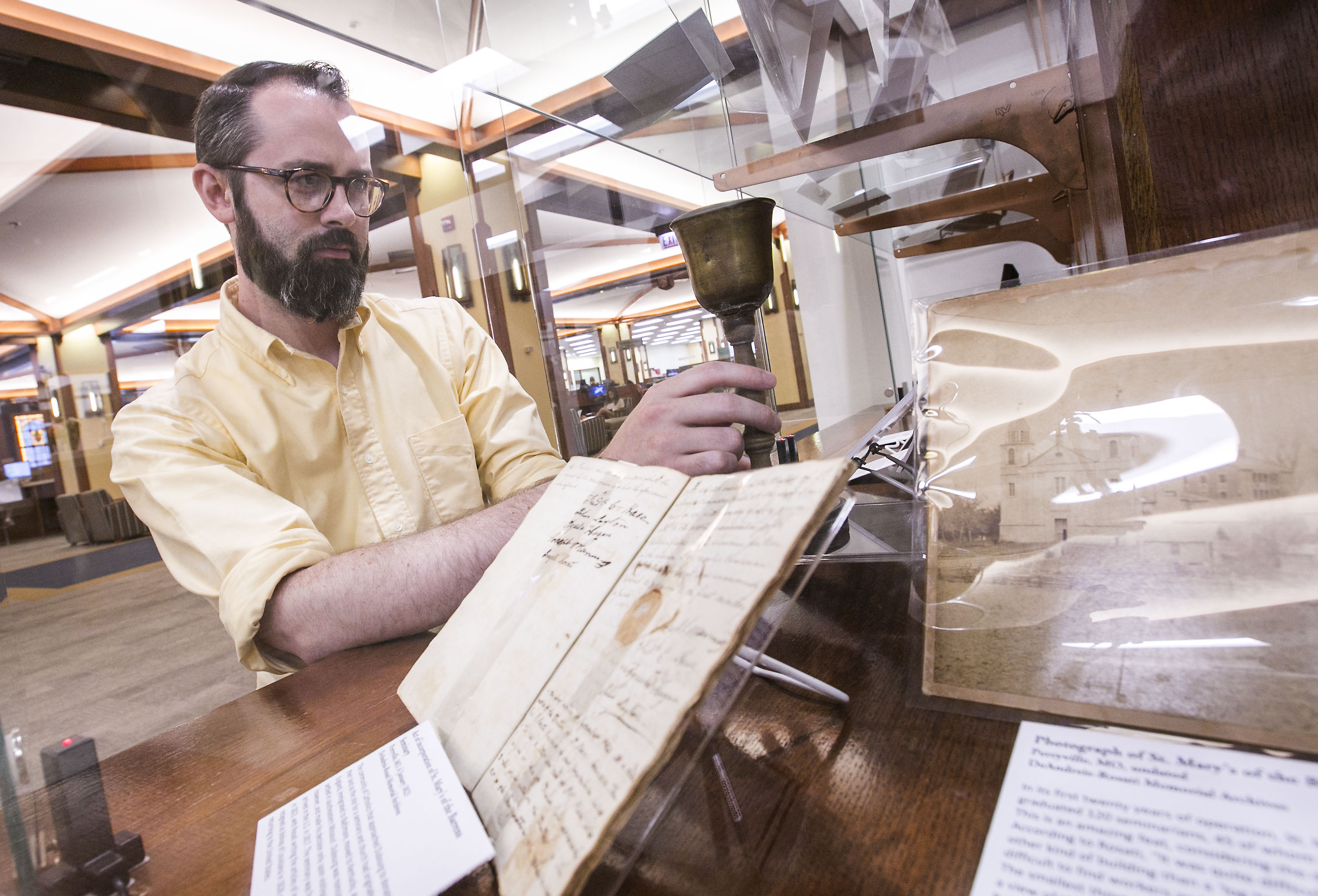 Andrew Rea, DePaul's Vincentian Librarian, places a small wooden chalice into a display case as he prepares for an exhibit of Vincentian artifacts at the John T. Richardson Library. (DePaul University/Jamie Moncrief)