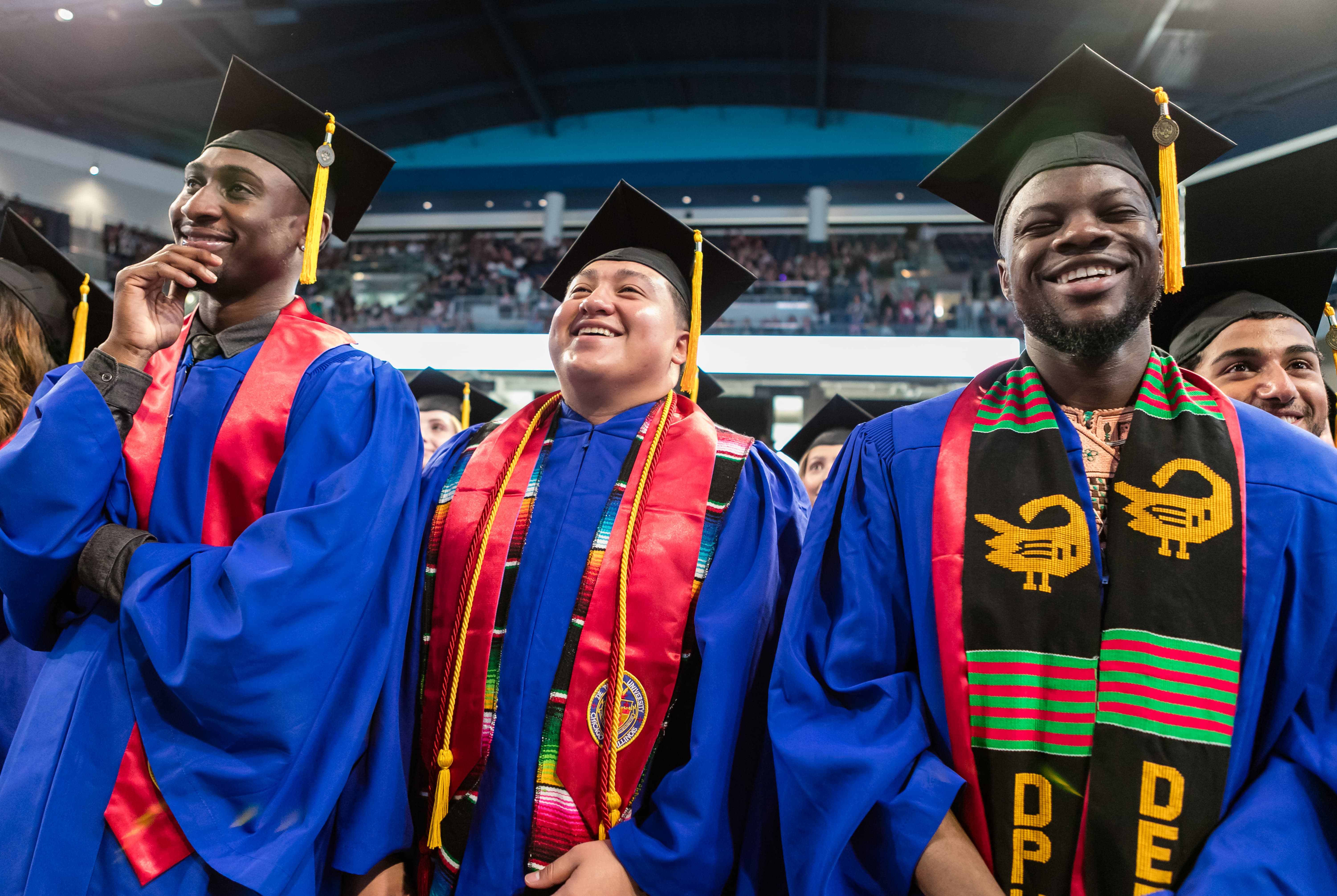 Three students stand at commencement Three students stand at commencement