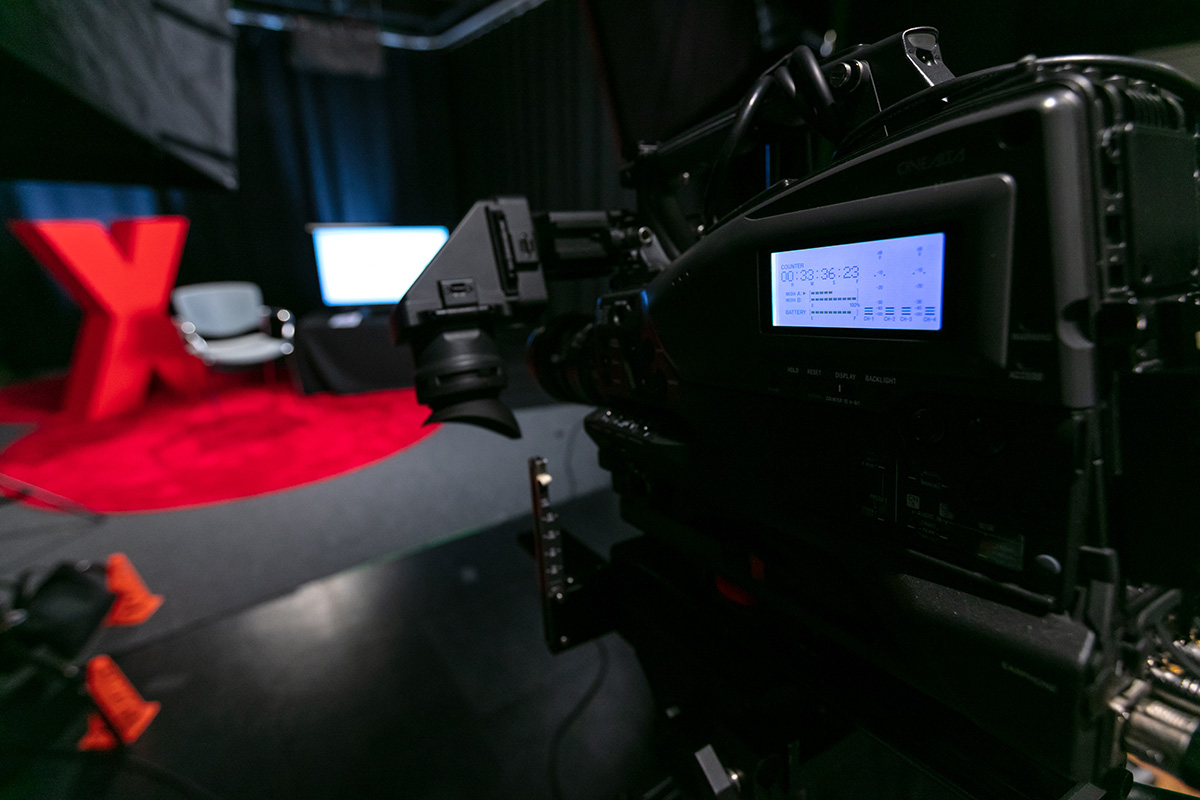 Camera in recording studio aimed at red TEDx X structure