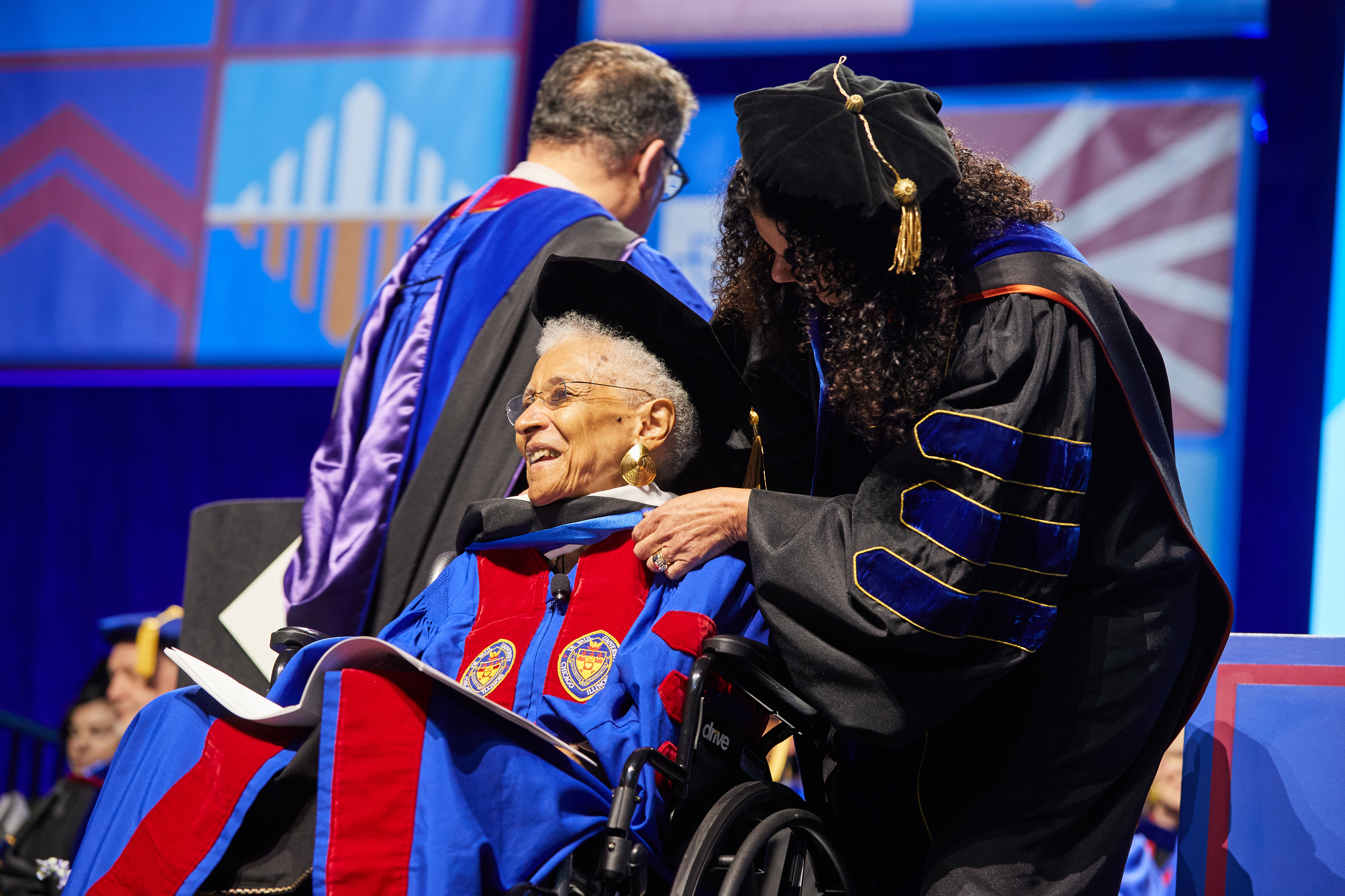 A seated woman is hooded for an honorary degree