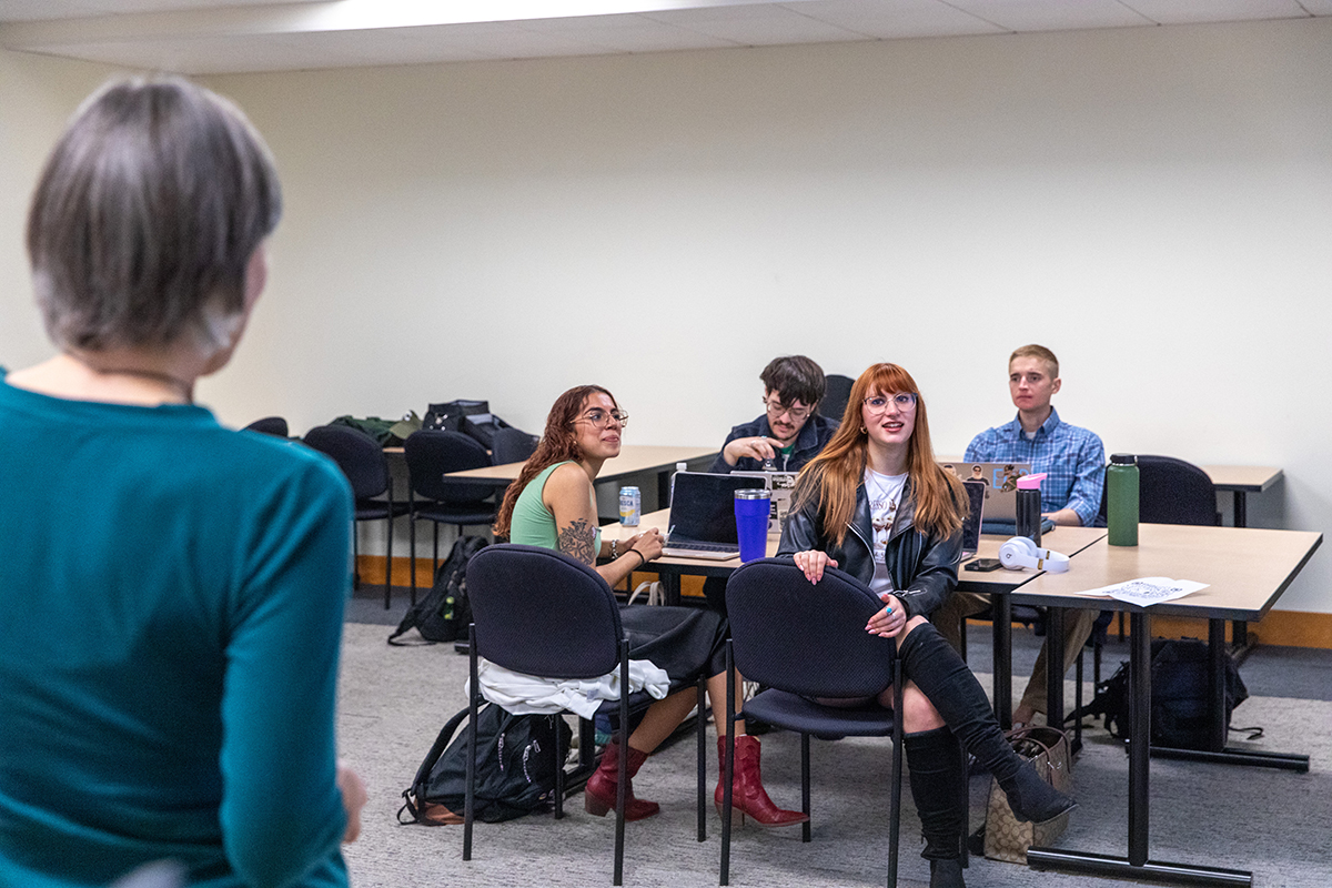 Hilary Conklin talks to four students in a classroom