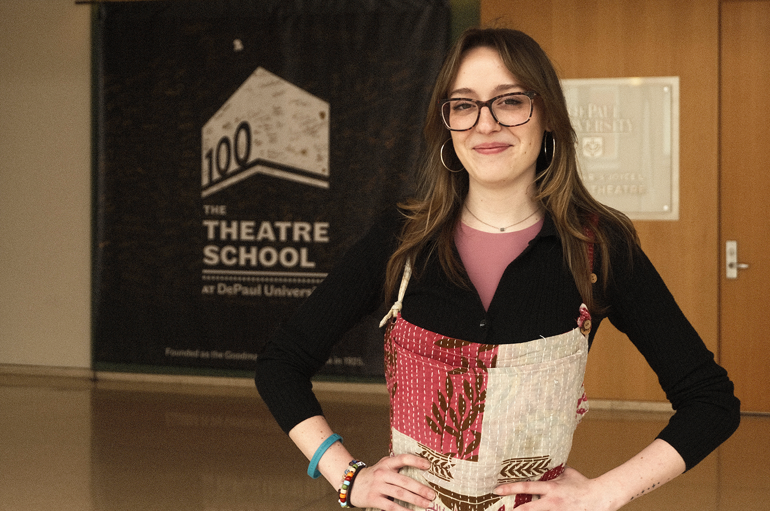 Student Sarah Johnson poses in front of a Theatre School centennial banner