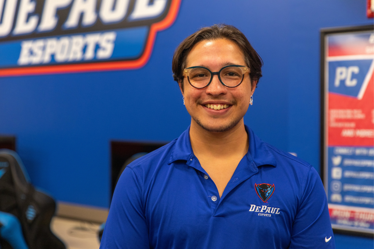 Jeffrey stands in the gaming hub with a DePaul esports logo in the background