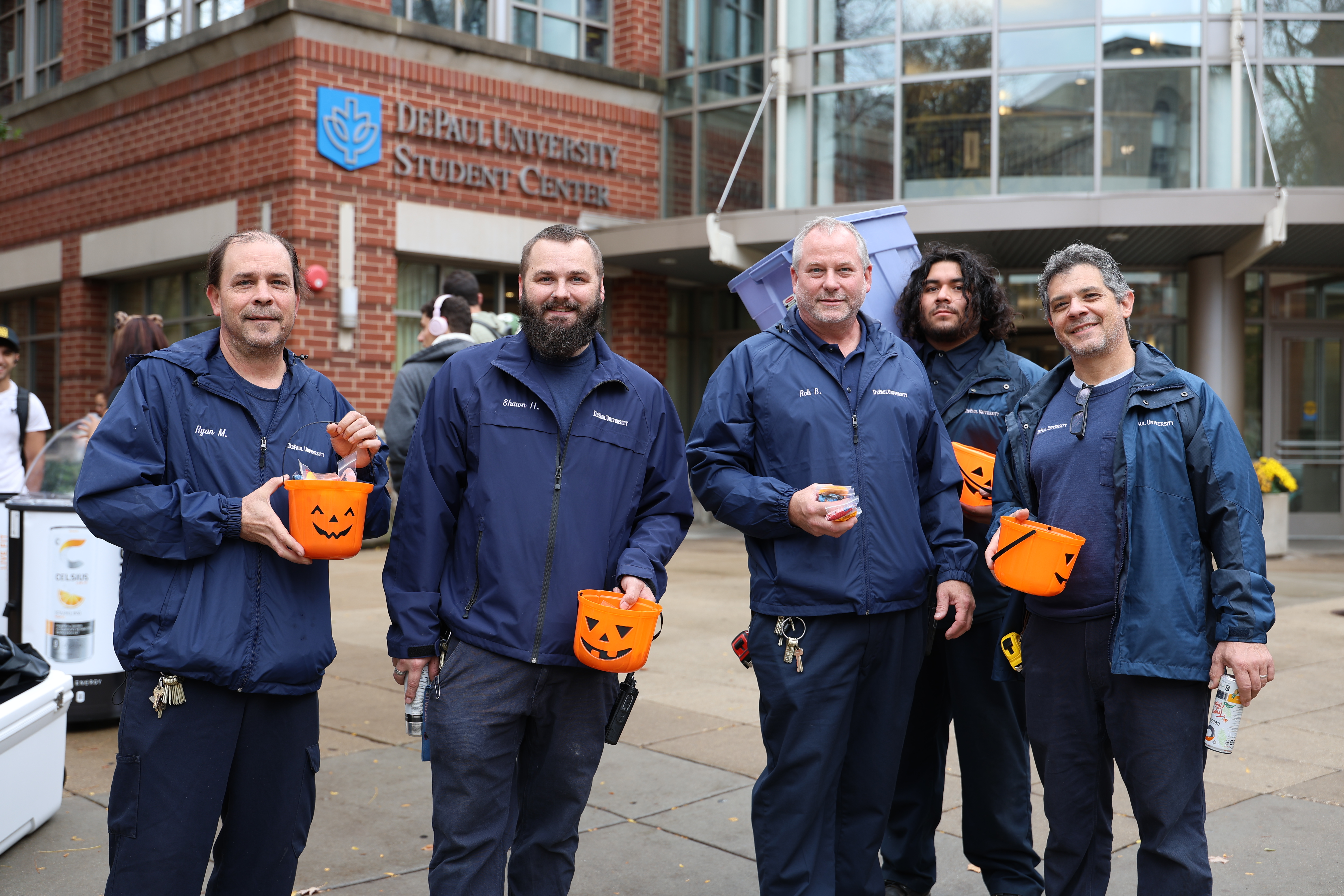 DePaul staff members pose for a photo with their halloween buckets full of candy to pass out to students.