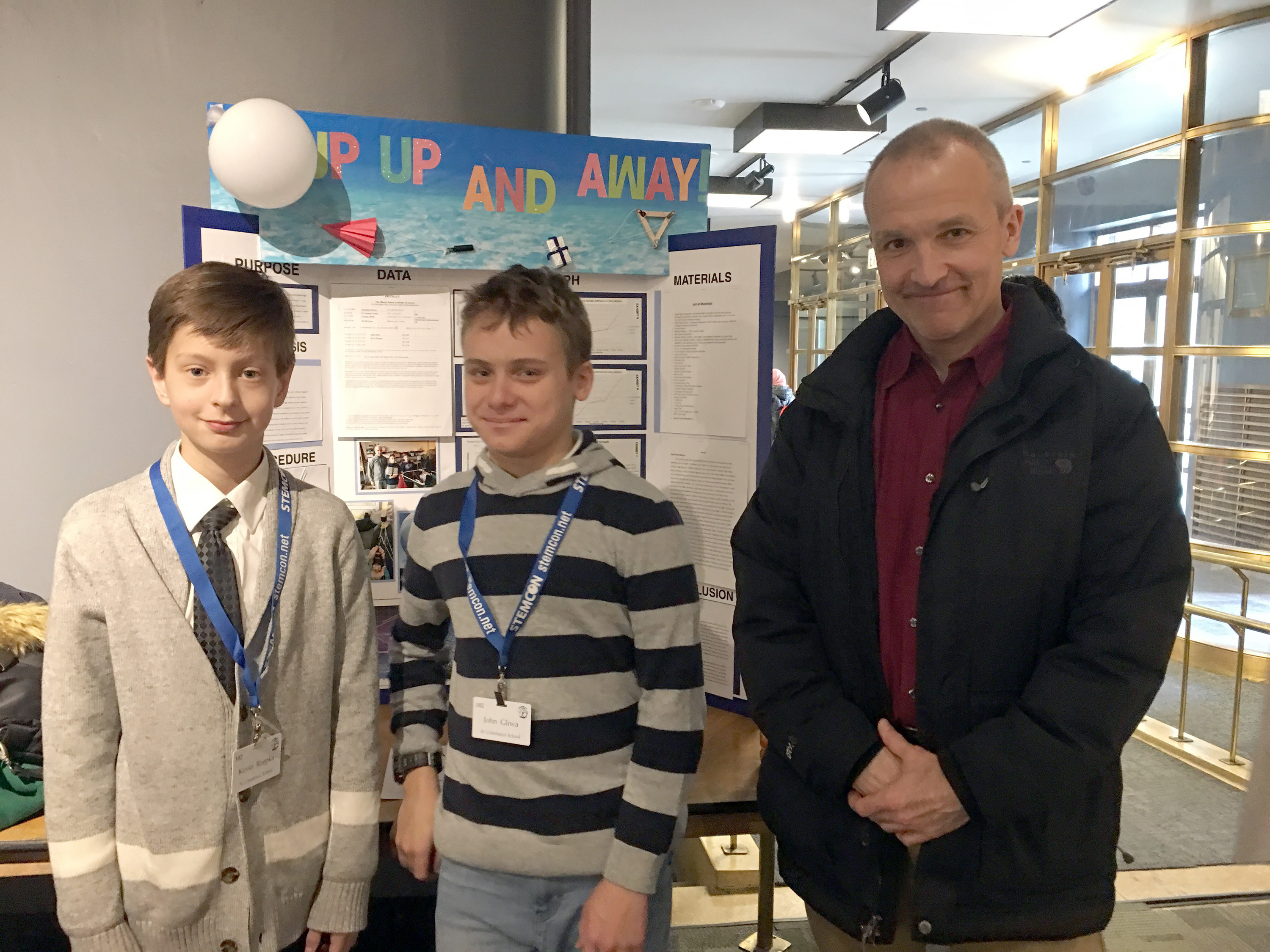 students and professor in front of science fair poster