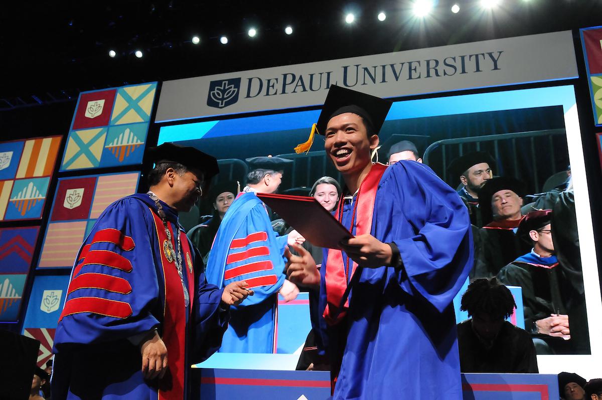 A graduate from the Driehaus College of Business celebrates while crossing the commencement stage at Wintrust Arena. (DePaul University/Jamie Moncrief)