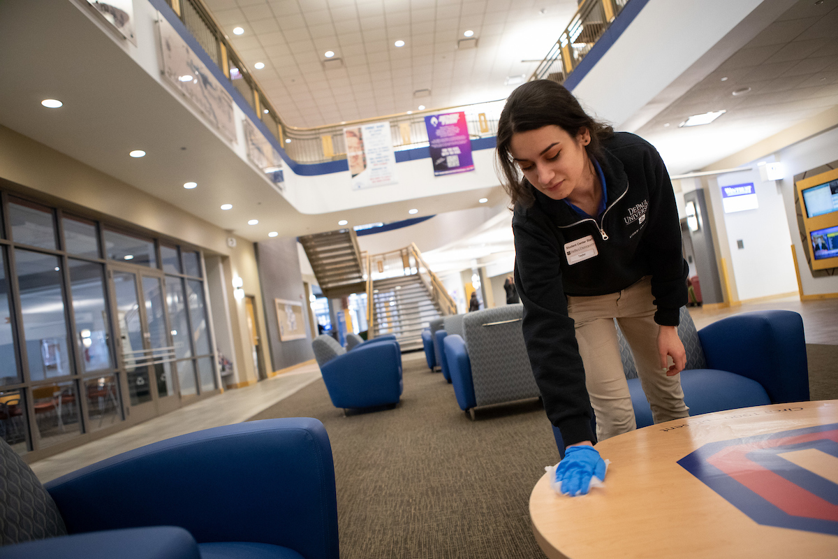 Student employee Taylor (CQ), wipes down a table with a cleaning wipe in the Lincoln Park Student Center