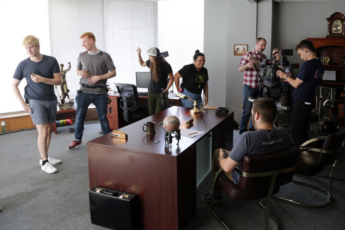 Crew working on a scene in a law office, setting up a camera