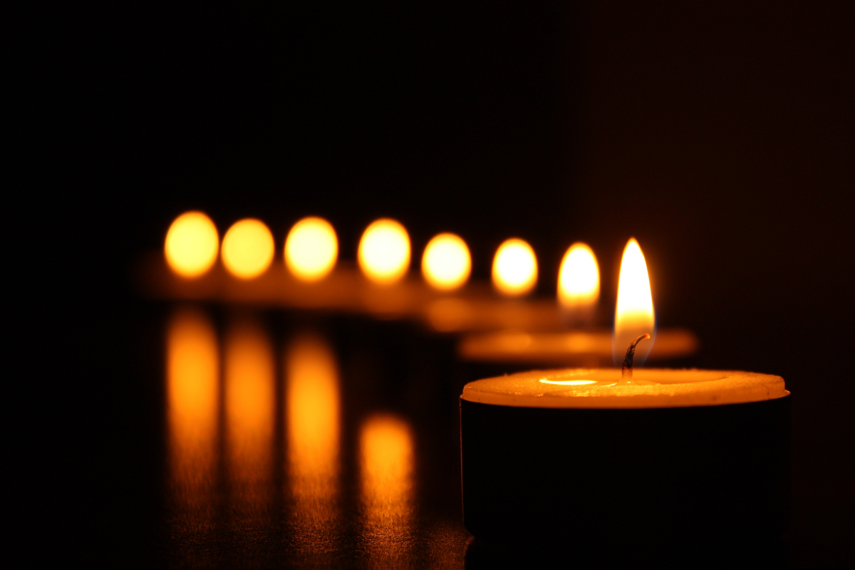A row of lit candles in a darkened space