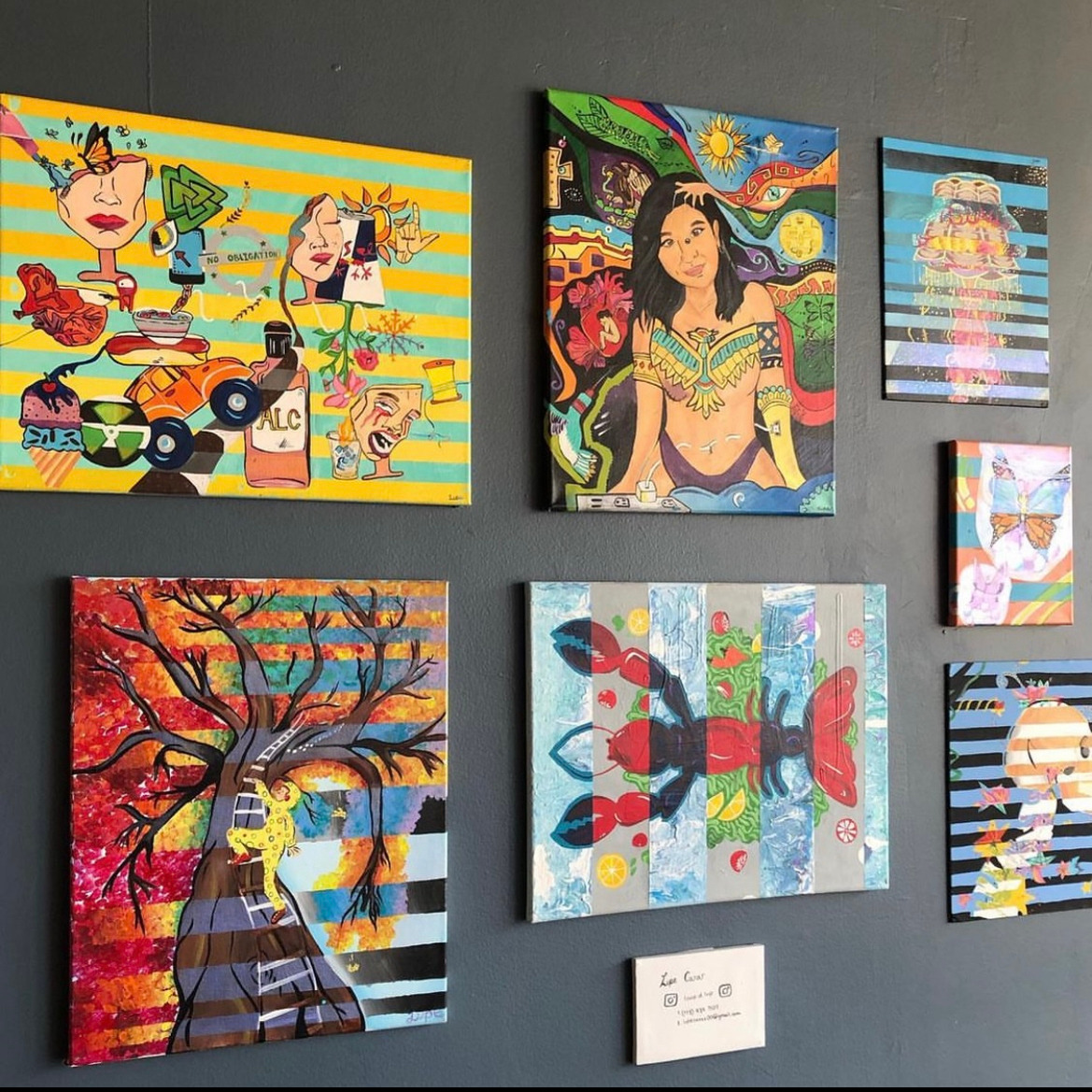 Several paintings by Lupe on a black wall in Cup of Joe Coffee Shop