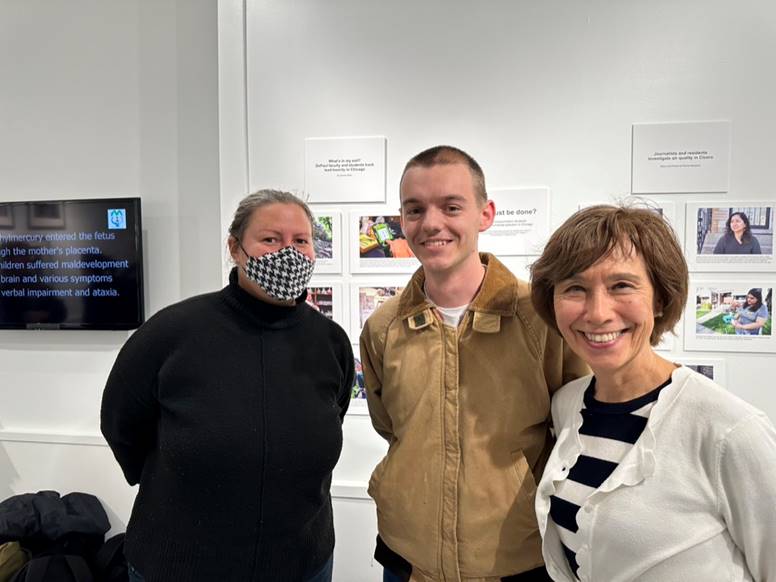 Robin Hoecker, Quentin Blais and Aileen Mioko Smith standing in front of student submitted photographs exhibited in the gallery.