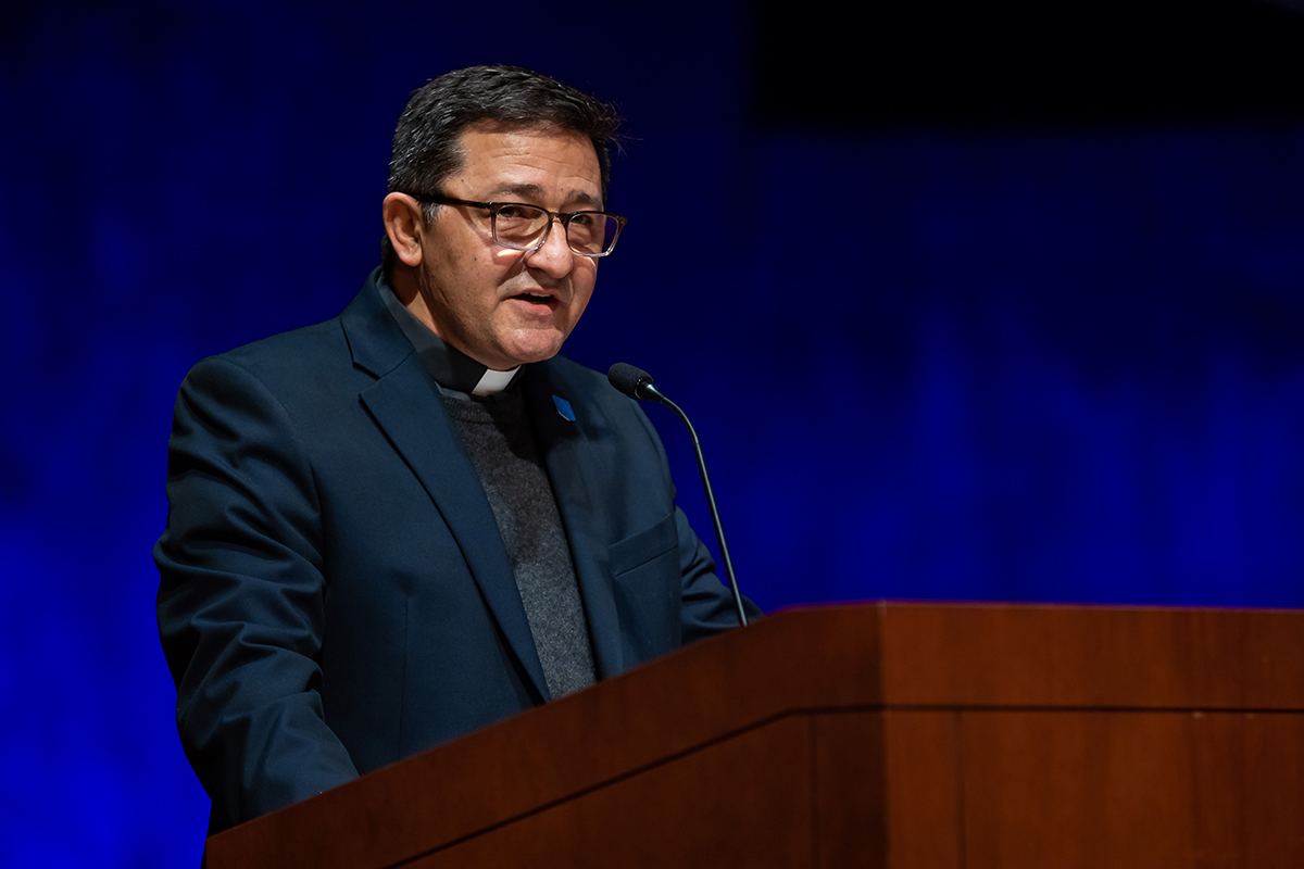Fr. Memo speaking at a podium