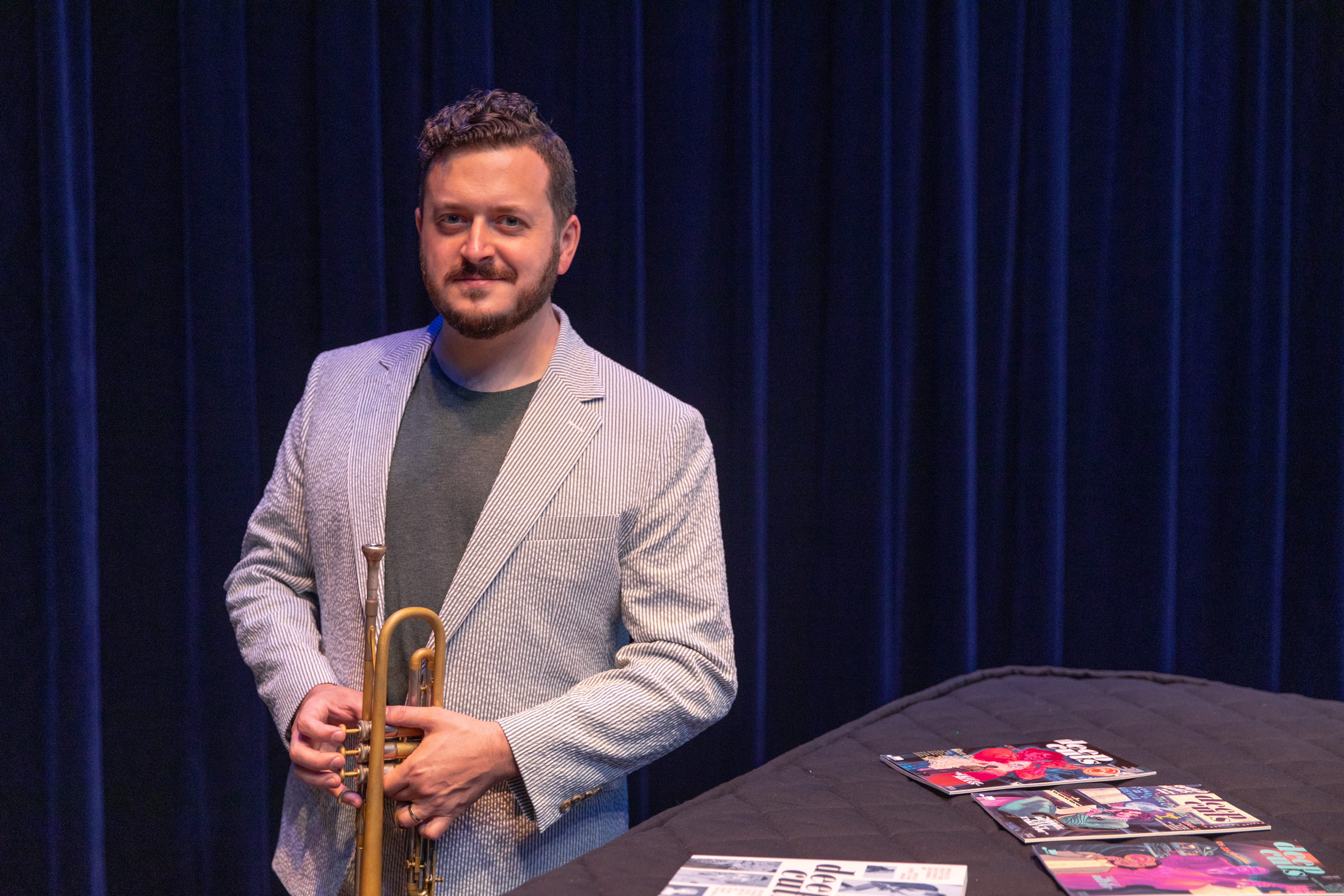 Man holding a trumpet standing next to comic books