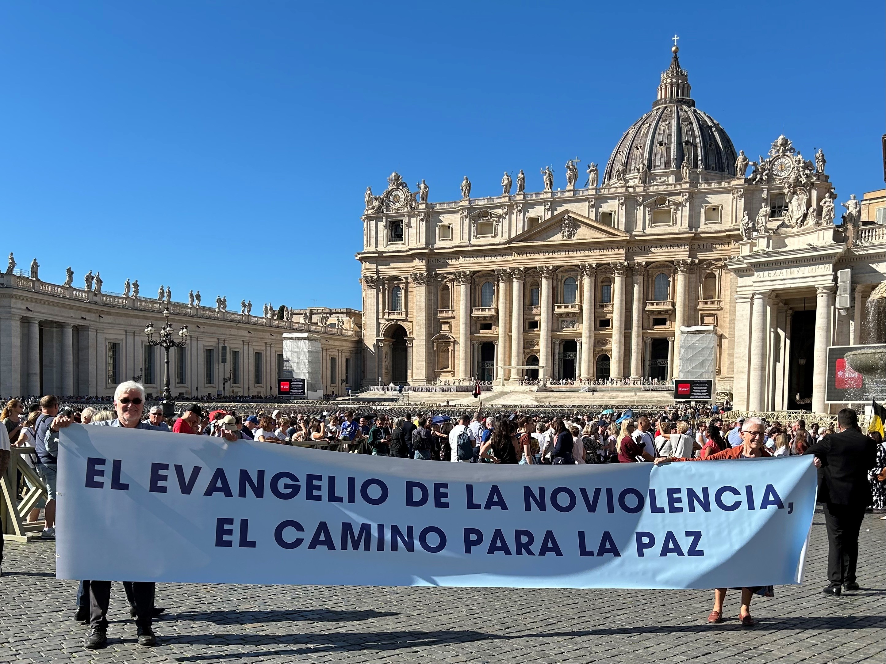 Ken Butigan (left) assists in holding a banner during a Sunday Angelus led by Pope Francis in St Peter’s Square. The sign reads “Gospel Nonviolence – The Way to Peace.”