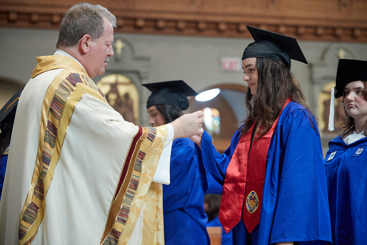 Father Joe Williams gives communion to a graduate