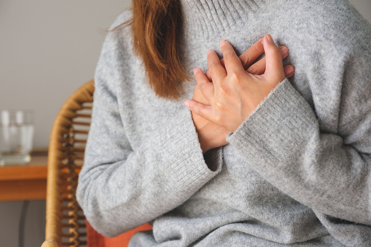 A woman holds her hands across her heart.