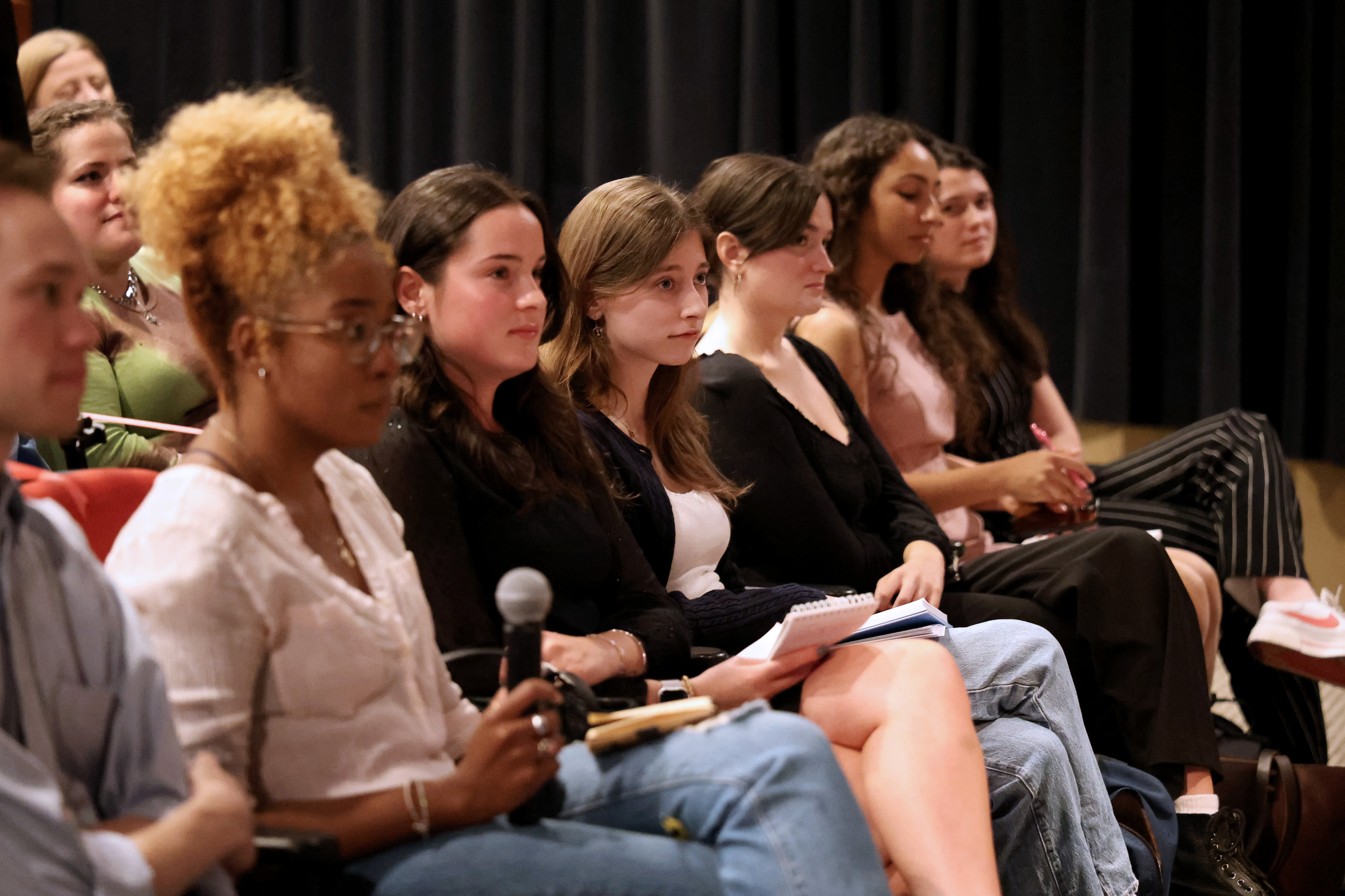 Student journalists sit in a row listening to a panel about covering hard topics. 