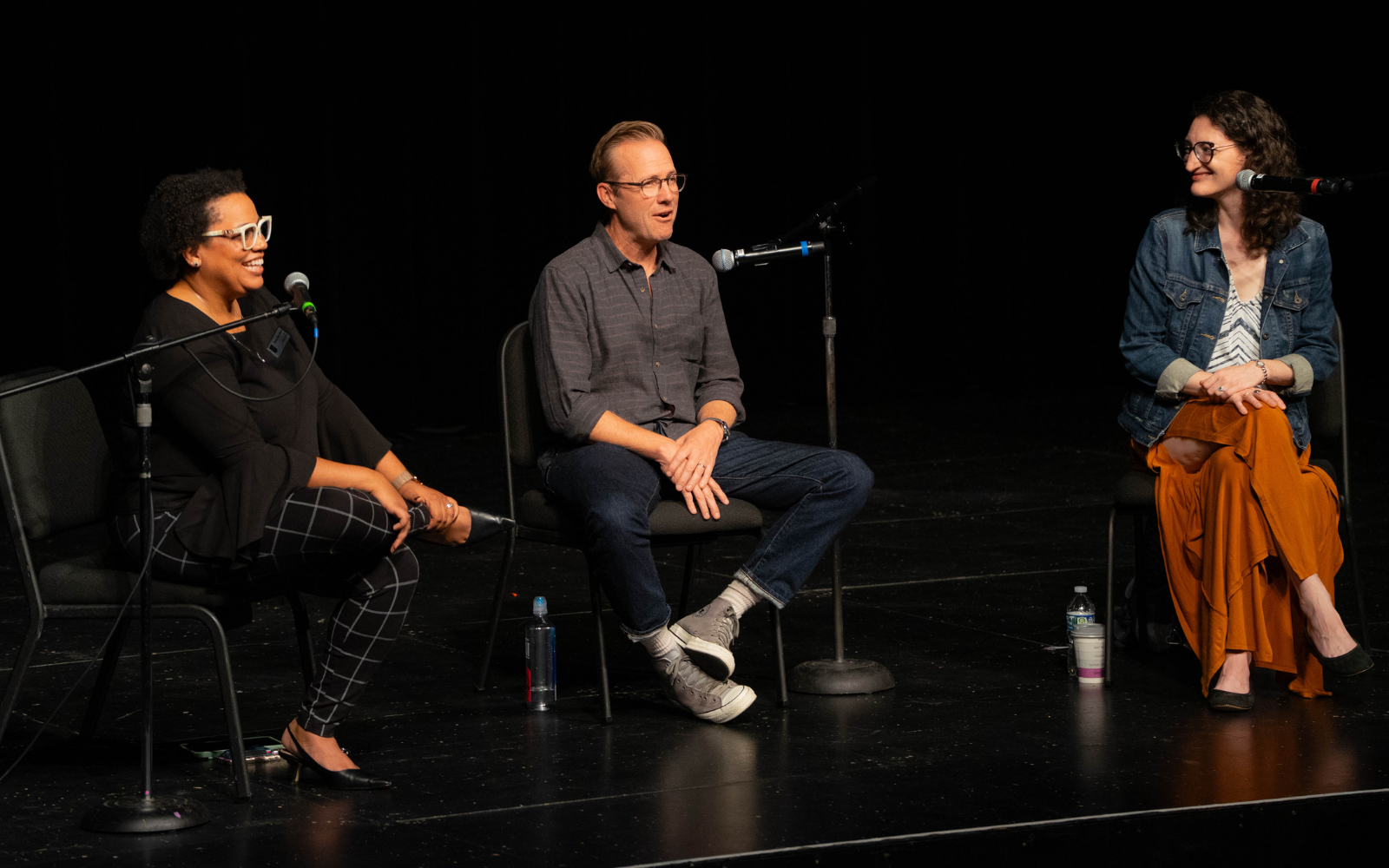 Three people sitting on a stage laughing Three people sitting on a stage laughing