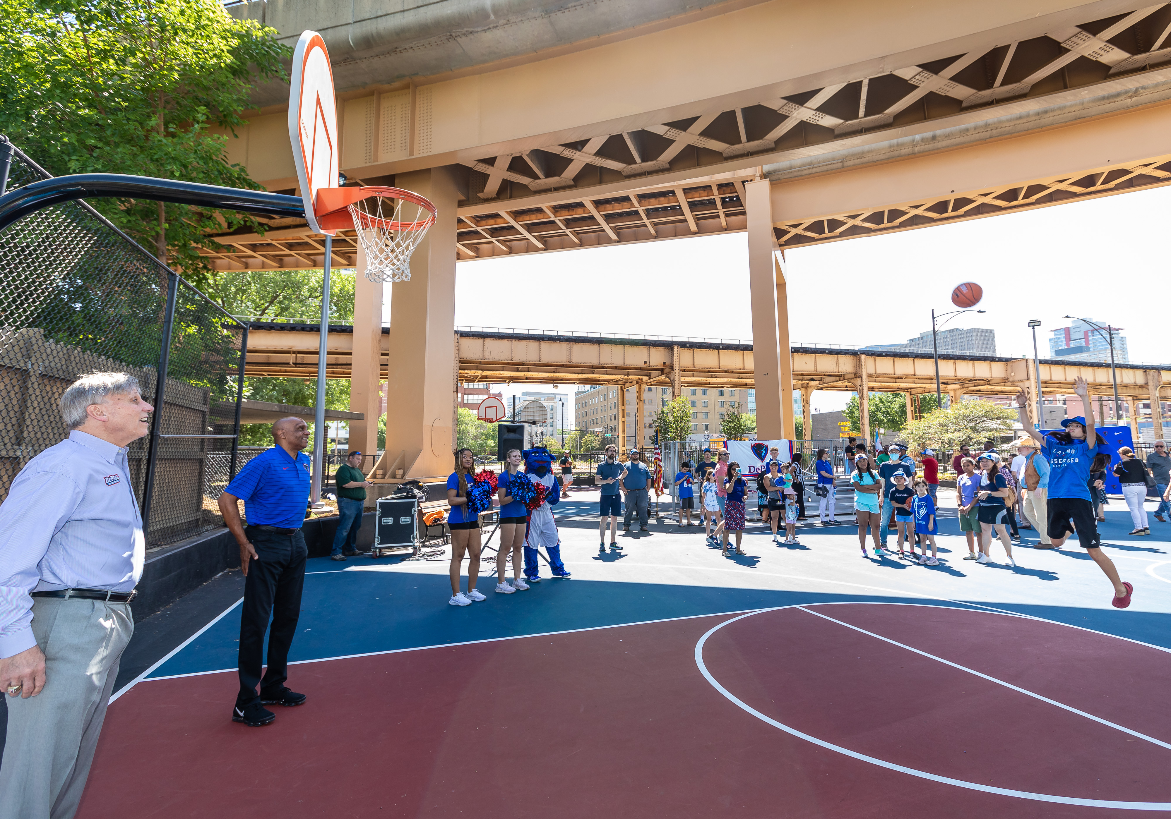 DePaul Basketball Head Coaches Doug Bruno, far left, and Tony Stubblefield, center, play basketball with community members during a grand opening.