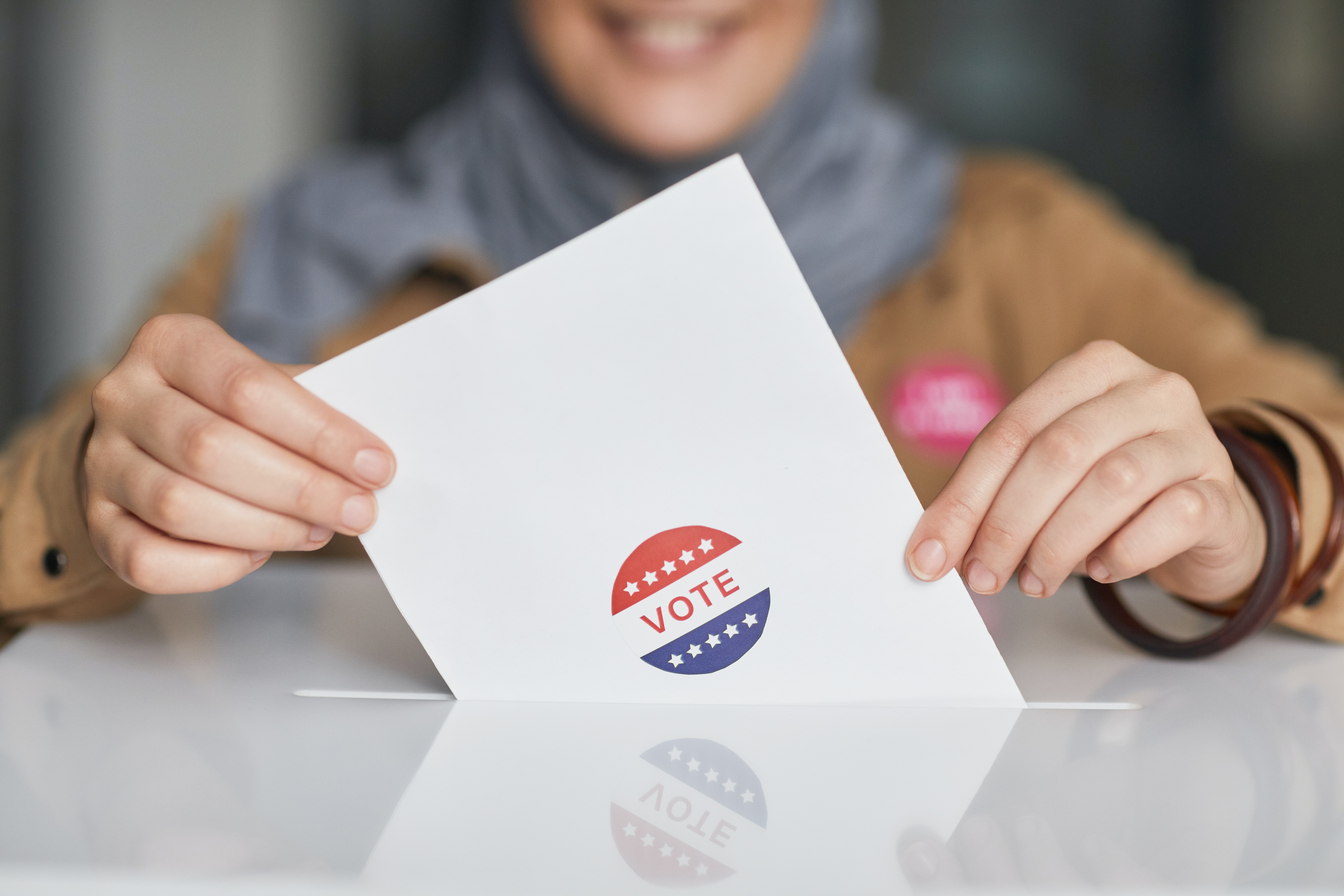 Female voter places a ballot into box.