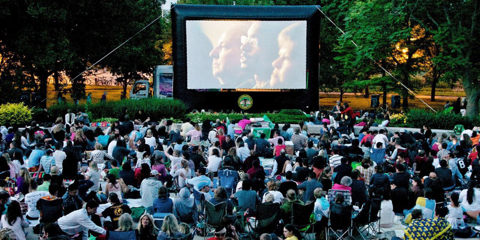 A crowd watches a movie in a Chicago park on a large screen