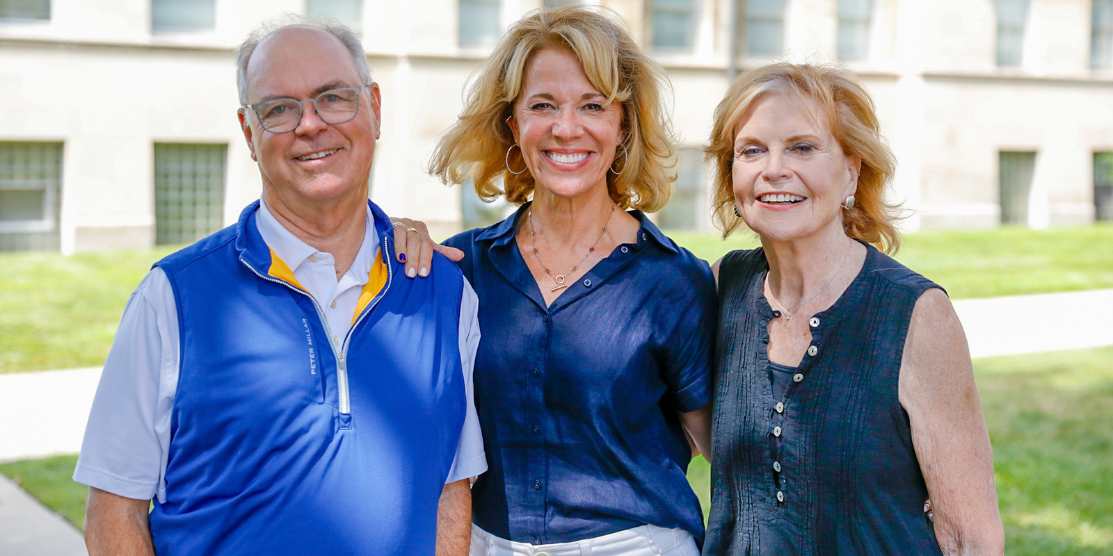 Two women and a man stand outside