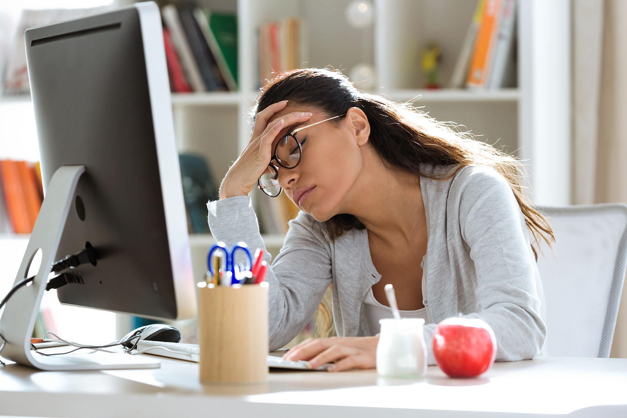 Woman looks fatigued sitting at a desk