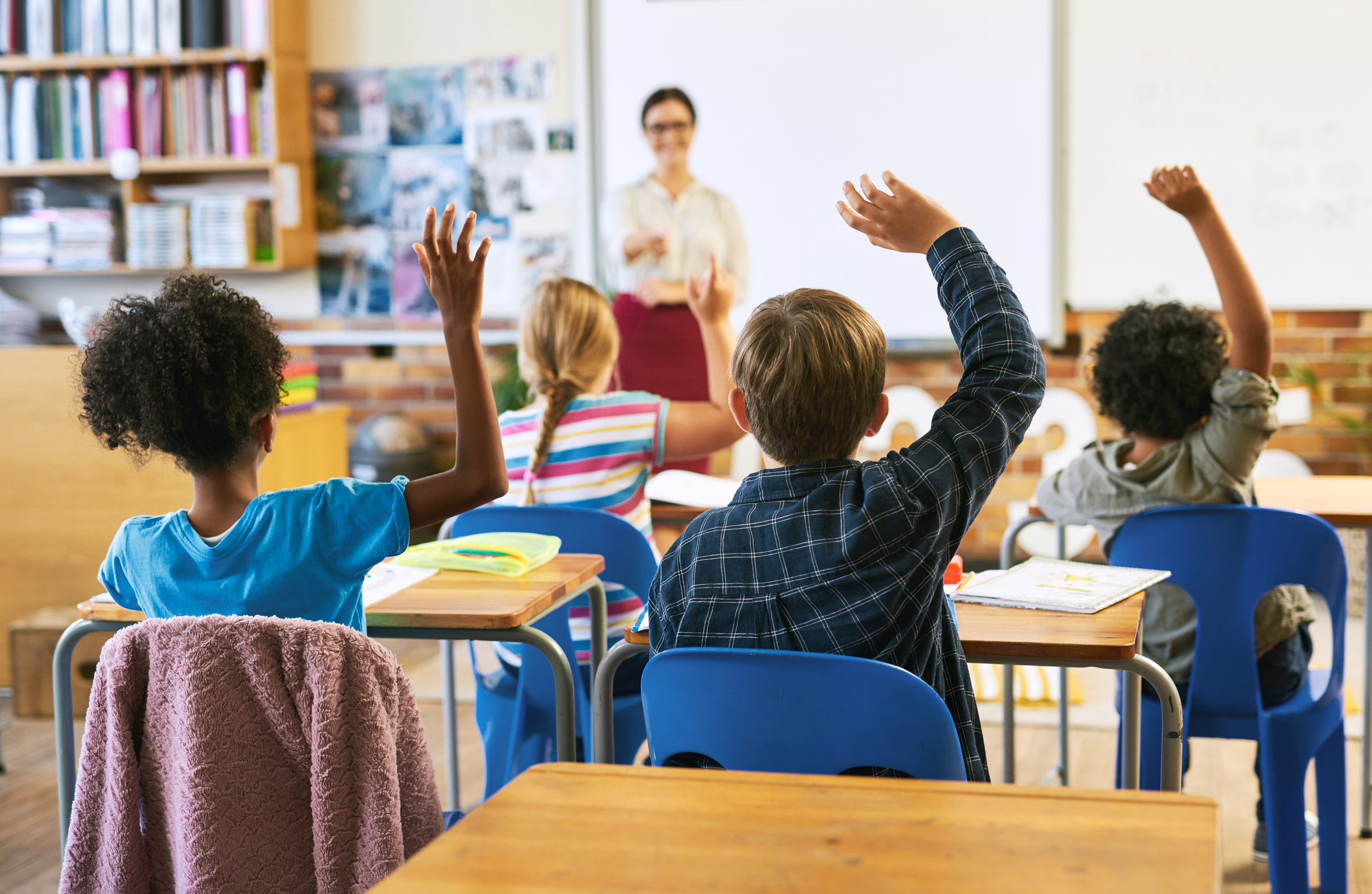 Children raising hands in a classroom
